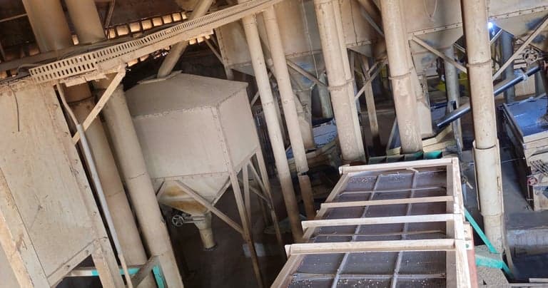 Overhead view of a dry mill: hoppers, cyclones and ducting above a screening deck.