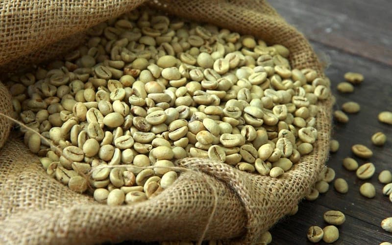 Green coffee beans in an open hessian sack.