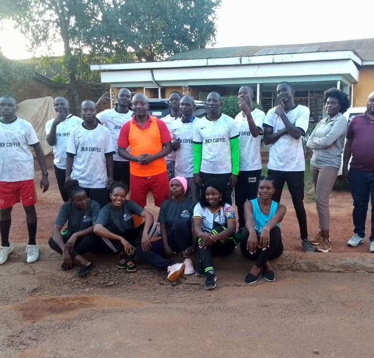 The Jber Coffee staff football team photographed together outside the workplace, men in Jber Coffee jerseys and women in team shirts.