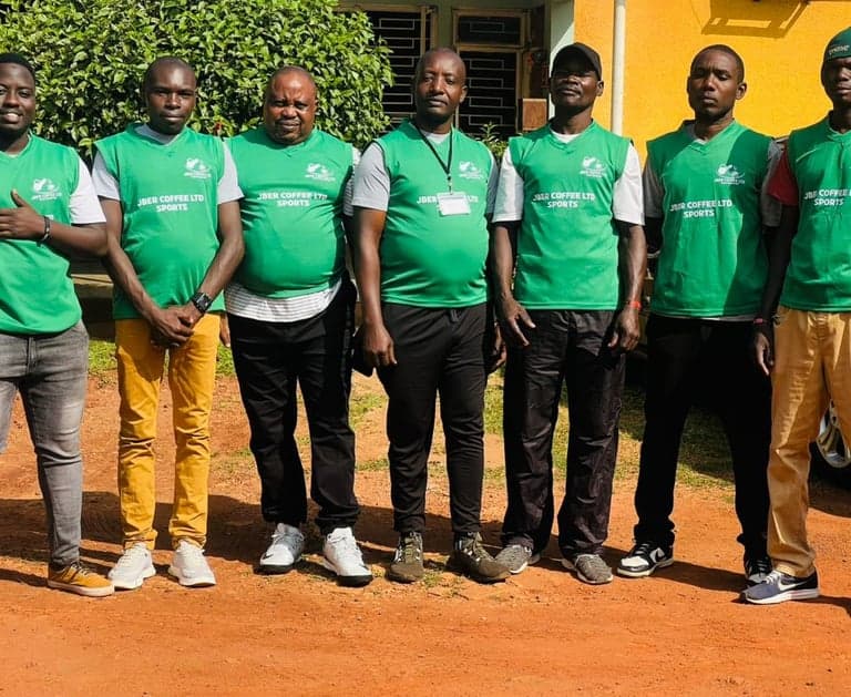 Staff in green Jber Coffee Ltd Sports vests standing together outside the workplace.